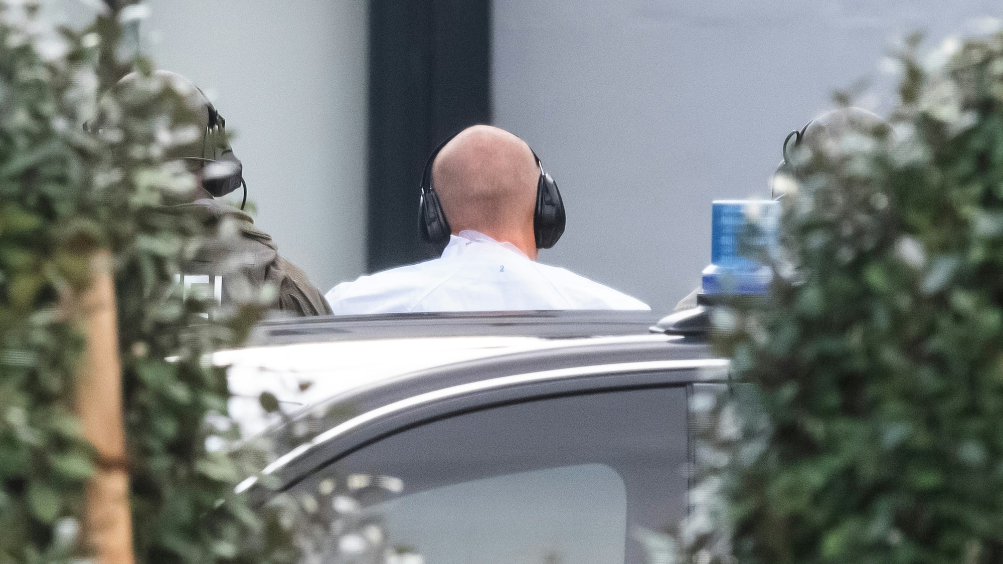Der Halle-Attentäter Stephan B. wird im Oktober 2019 zur Außenstelle des Bundesgerichtshofs gebracht, er hat einen Ohrschutz auf und ist von hinten zu sehen.