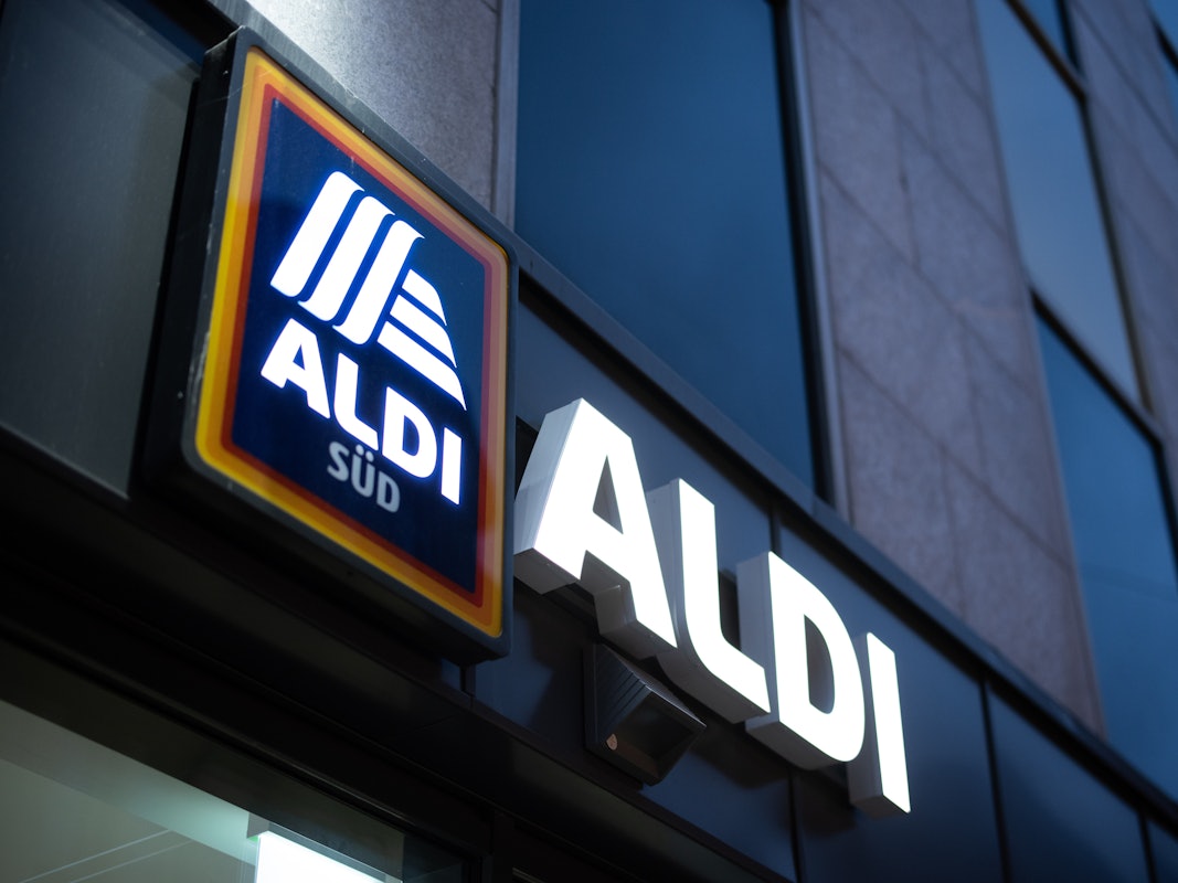 Das Logo einer Aldi Süd Filiale, fotografiert im November 2020 in einer Fußgängerzone der Düsseldorfer Innenstadt. Das Logo leuchtet, es ist Abend.