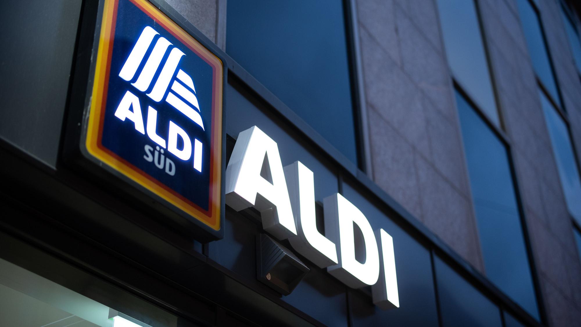 Das Logo einer Aldi Süd Filiale, fotografiert im November 2020 in einer Fußgängerzone der Düsseldorfer Innenstadt. Das Logo leuchtet, es ist Abend.
