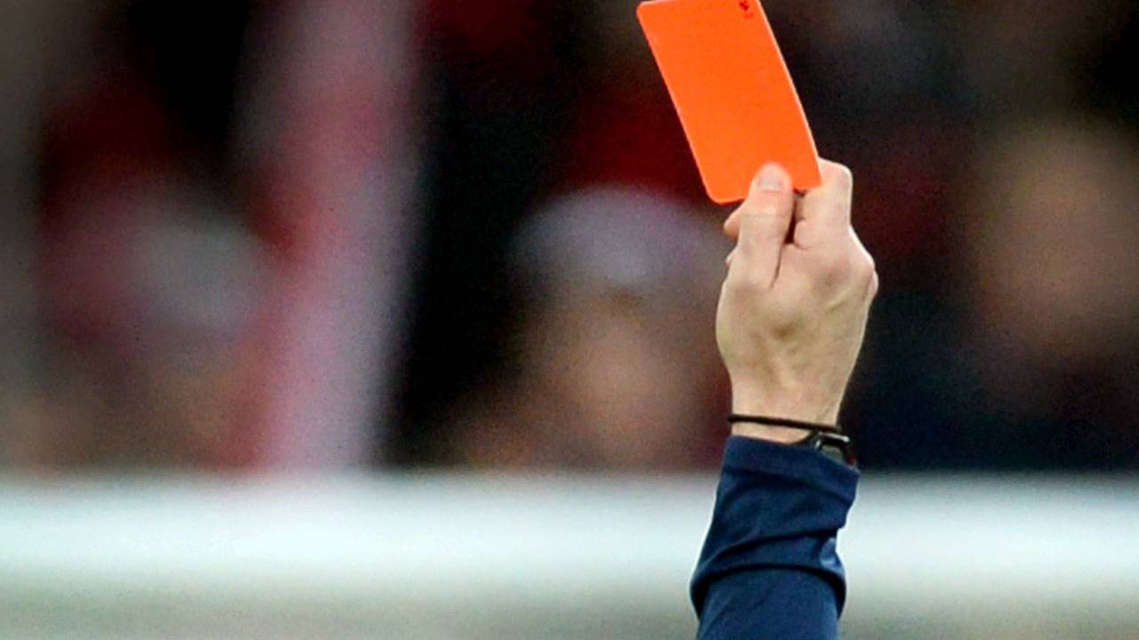 Ein Schiedsrichter zeigt einem Fußballspieler die Rote Karte.