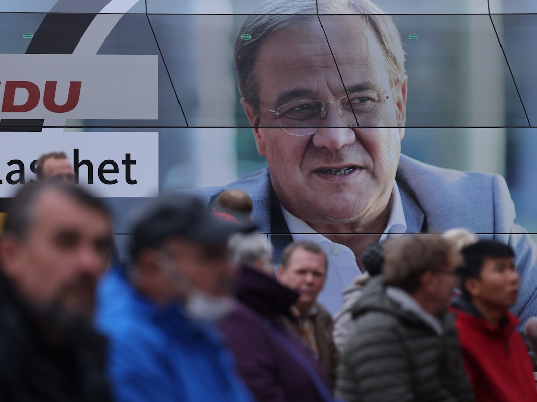 Mehrere Zuhörer stehen am 21. September neben einem Wahlkampfbus in Stralsund, um bei einer Wahlkampfkundgebung mit Bundeskanzlerin Angela Merkel und dem CDU-Kanzlerkandidaten Armin Laschet teilzunehmen.