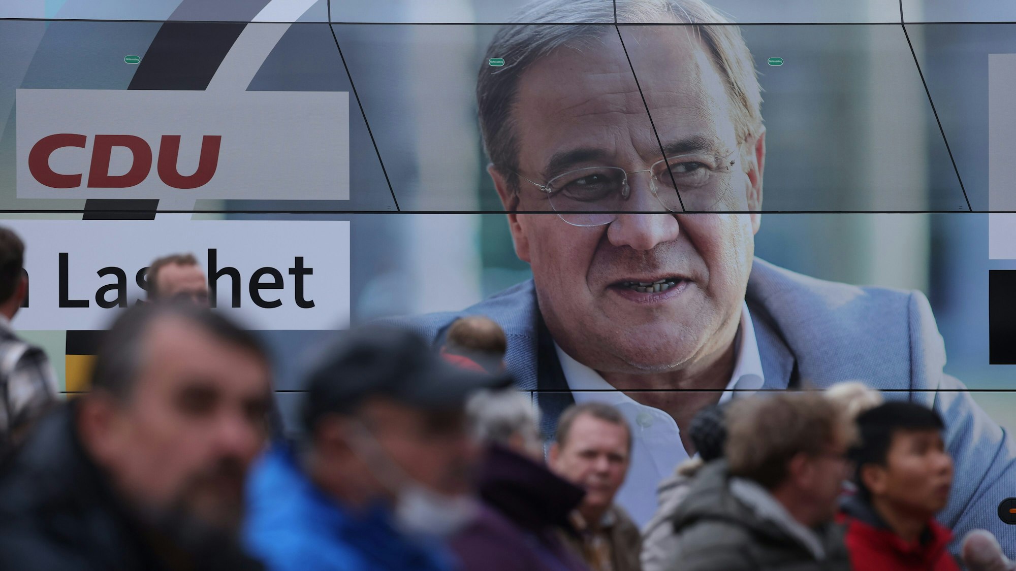 Mehrere Zuhörer stehen am 21. September neben einem Wahlkampfbus in Stralsund, um bei einer Wahlkampfkundgebung mit Bundeskanzlerin Angela Merkel und dem CDU-Kanzlerkandidaten Armin Laschet teilzunehmen.