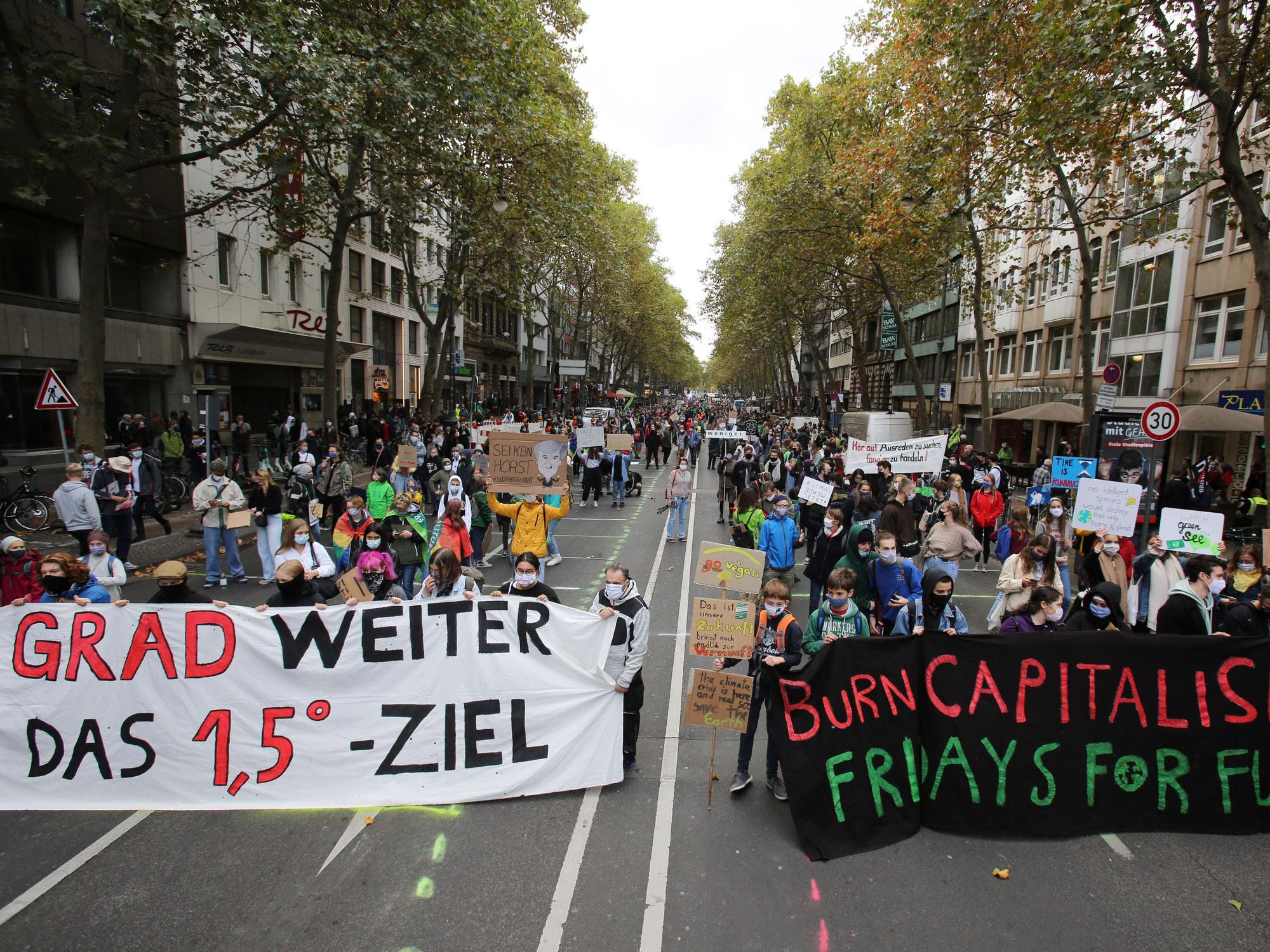 Hinter zwei großen Bannern stehe tausende Demonstranten einer Fridays for Future Demo.