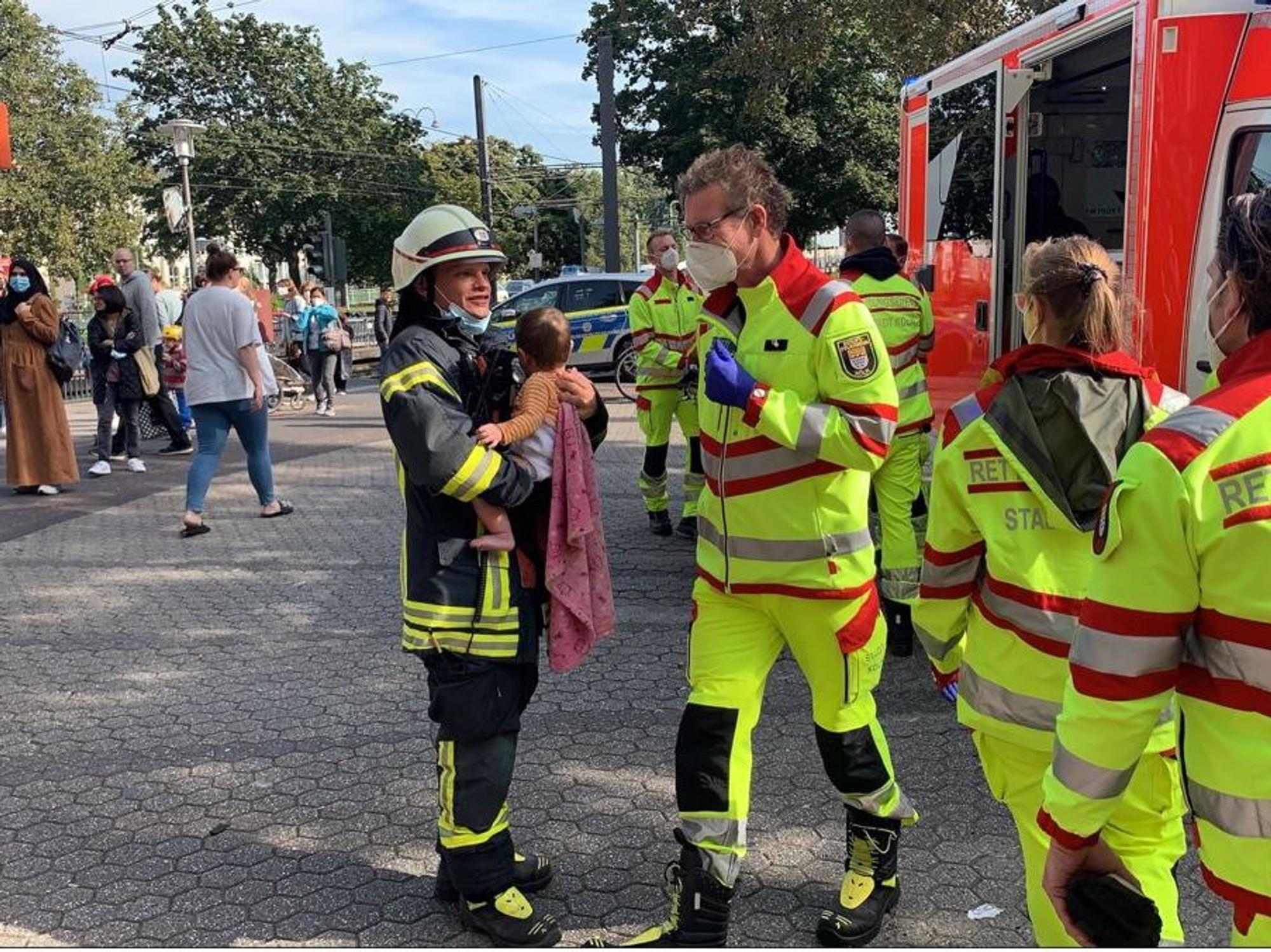 Eine Feuerwehrfrau hält ein Kleinkind auf dem Arm.