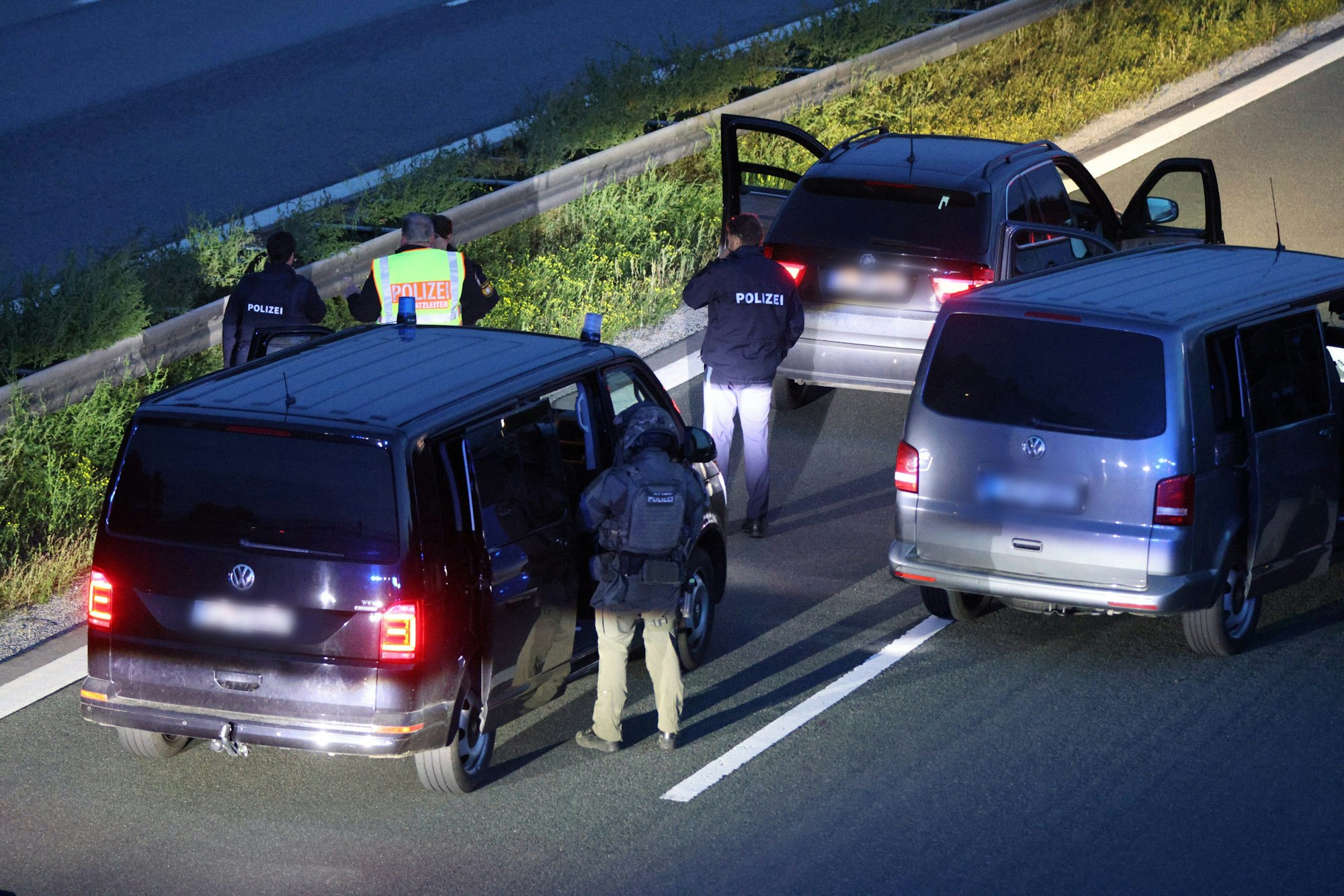 Einsatzkräfte der Polizei stehen mit ihren Fahrzeugen auf der Autobahn.