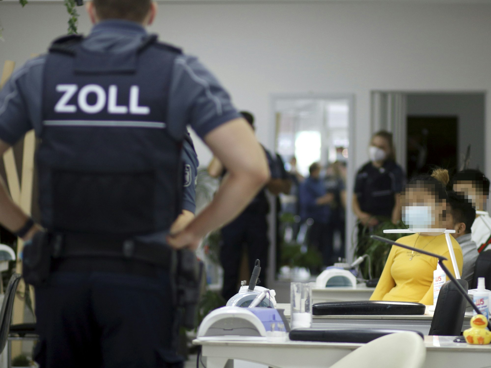 Ein Zollfahnder steht mit den Händen in Hüften in einem Nagelstudio in Köln.