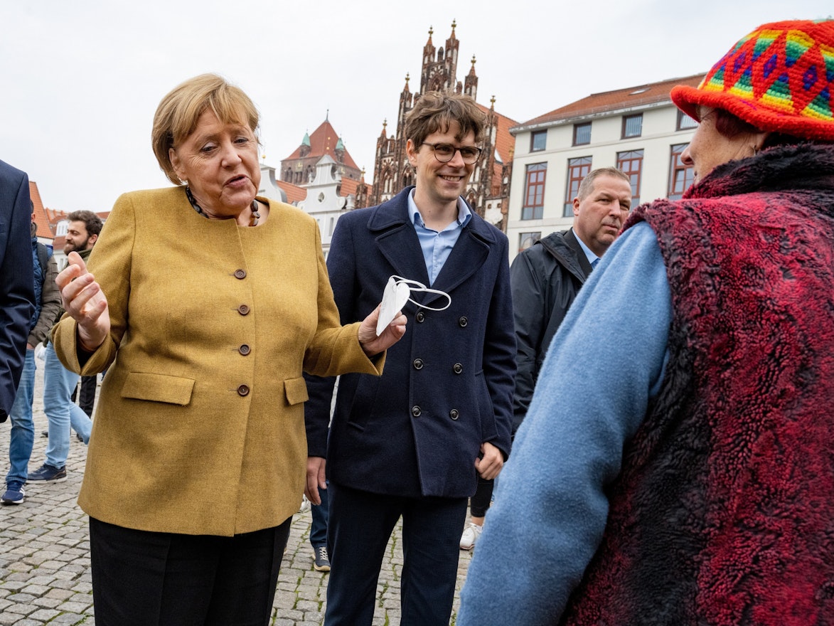 Bundeskanzlerin Angela Merkel (l., CDU) und Georg Günther (CDU), Vorsitzender der Jungen Union Mecklenburg-Vorpommerns, bei einem Überraschungsbesuch auf dem Wochenmarkt von Greifswald. Merkel spricht mit der Blumenhändlerin Edeltraud Honig, es sind schöne Worte des Abschieds.