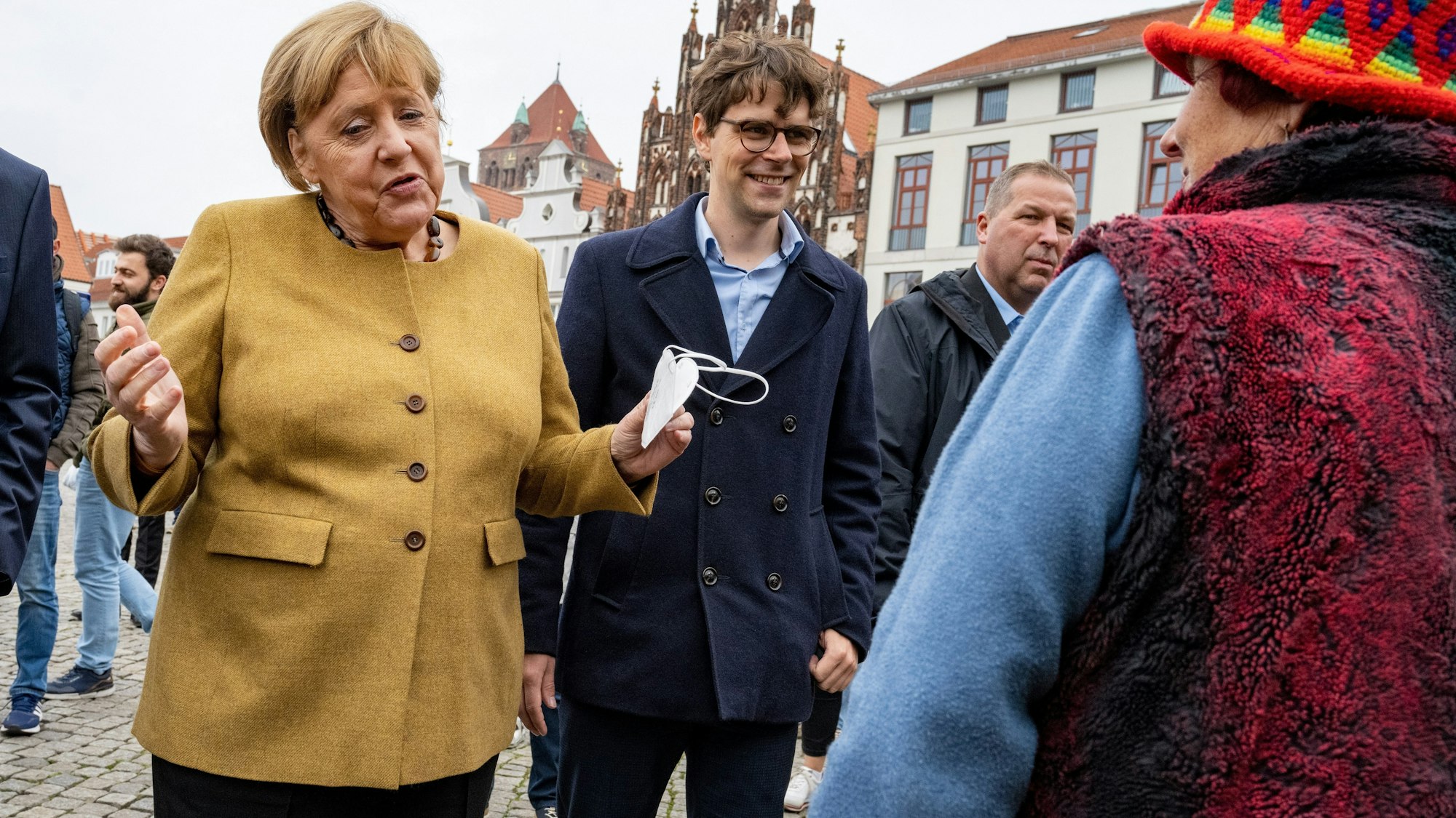 Bundeskanzlerin Angela Merkel (l., CDU) und Georg Günther (CDU), Vorsitzender der Jungen Union Mecklenburg-Vorpommerns, bei einem Überraschungsbesuch auf dem Wochenmarkt von Greifswald. Merkel spricht mit der Blumenhändlerin Edeltraud Honig, es sind schöne Worte des Abschieds.