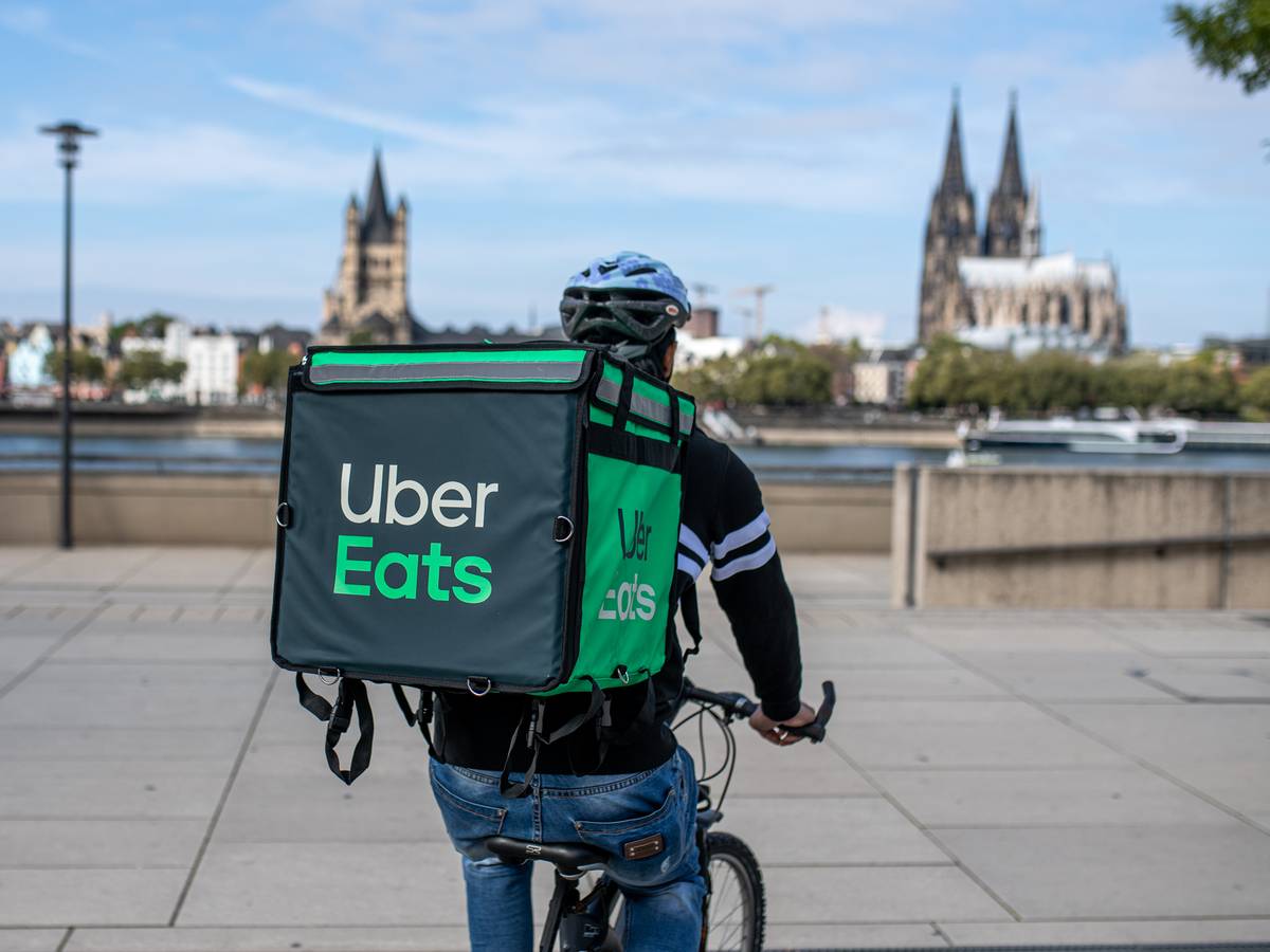 Ein Radfahrer mit großer Essenstasche von Uber Eats auf dem Rücken.