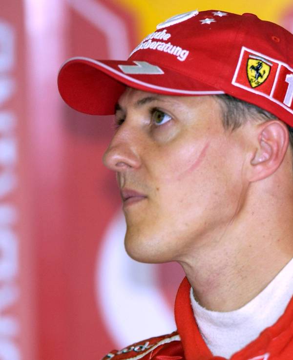 Michael Schumacher trägt einen roten Ferrari-Anzug eine rote Ferrari-Kappe.