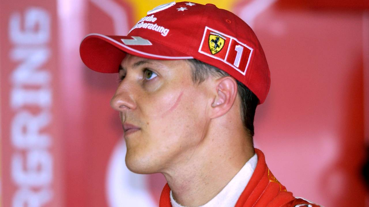 Michael Schumacher trägt einen roten Ferrari-Anzug eine rote Ferrari-Kappe.
