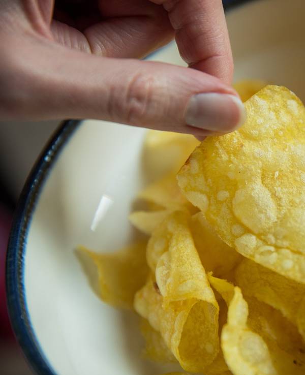 Eine Frau greift nach Kartoffelchips.