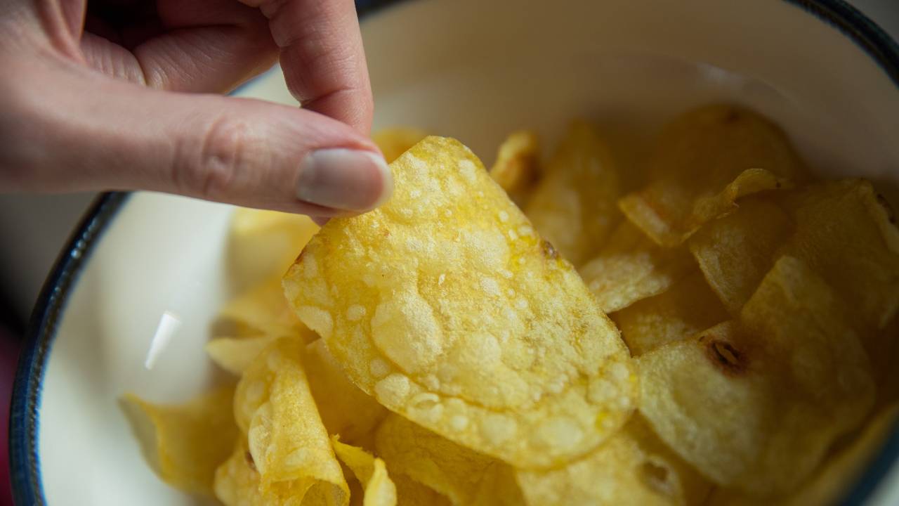 Eine Frau greift nach Kartoffelchips.