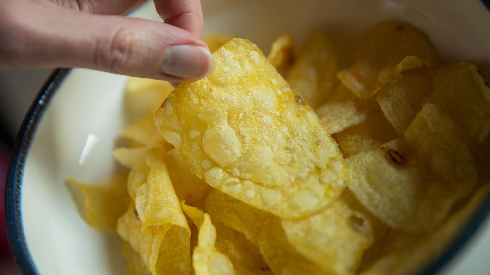 Eine Frau greift nach Kartoffelchips.