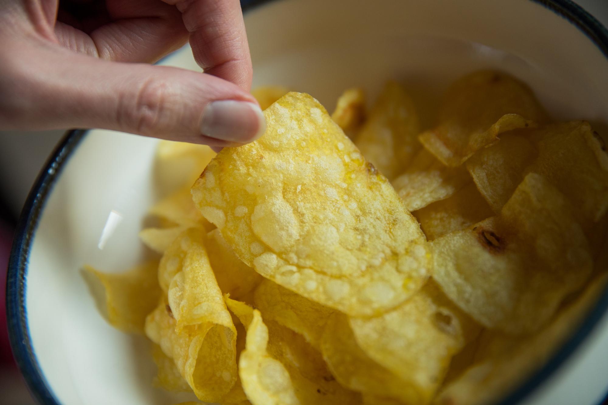Eine Frau greift nach Kartoffelchips.