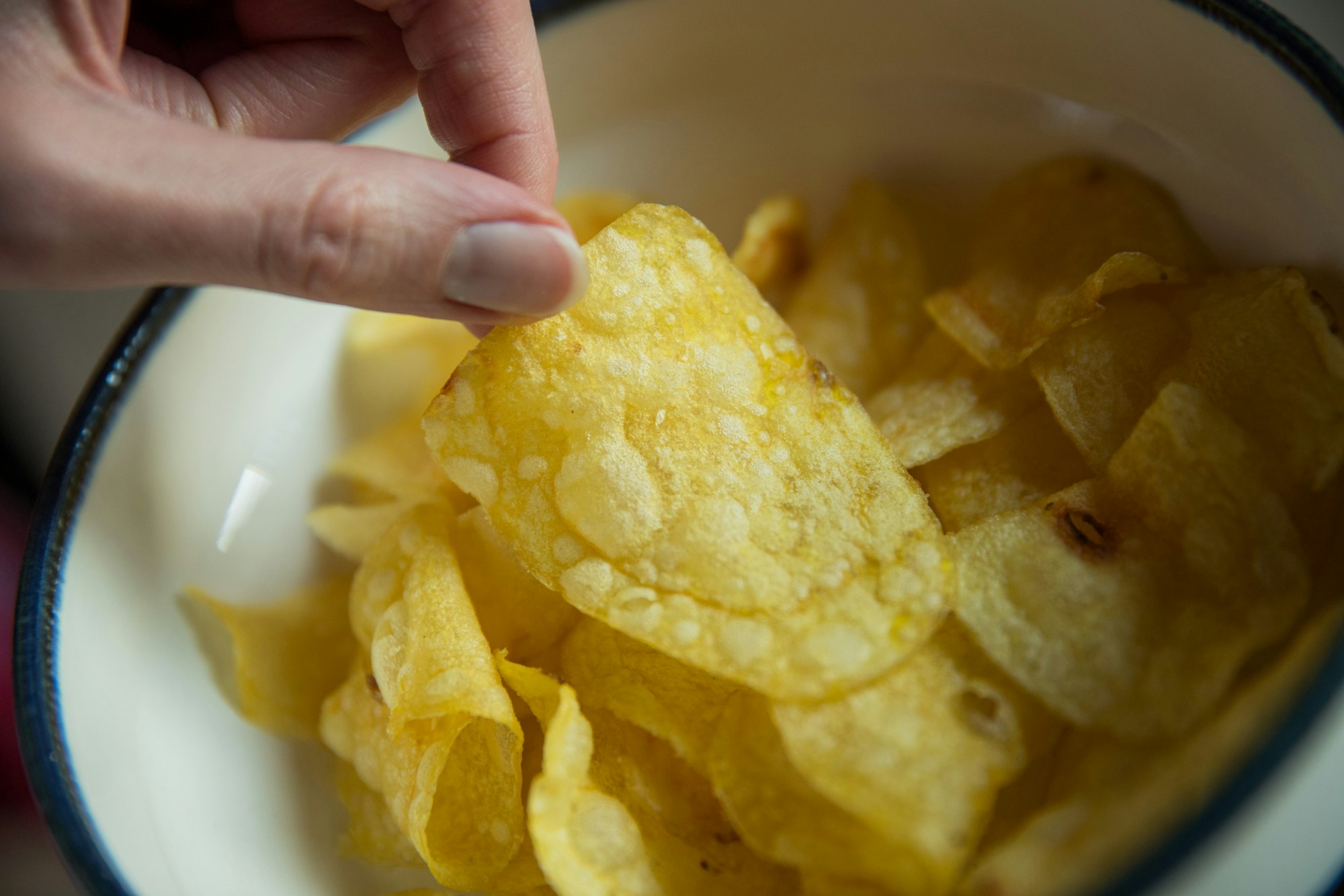 Eine Frau greift nach Kartoffelchips.