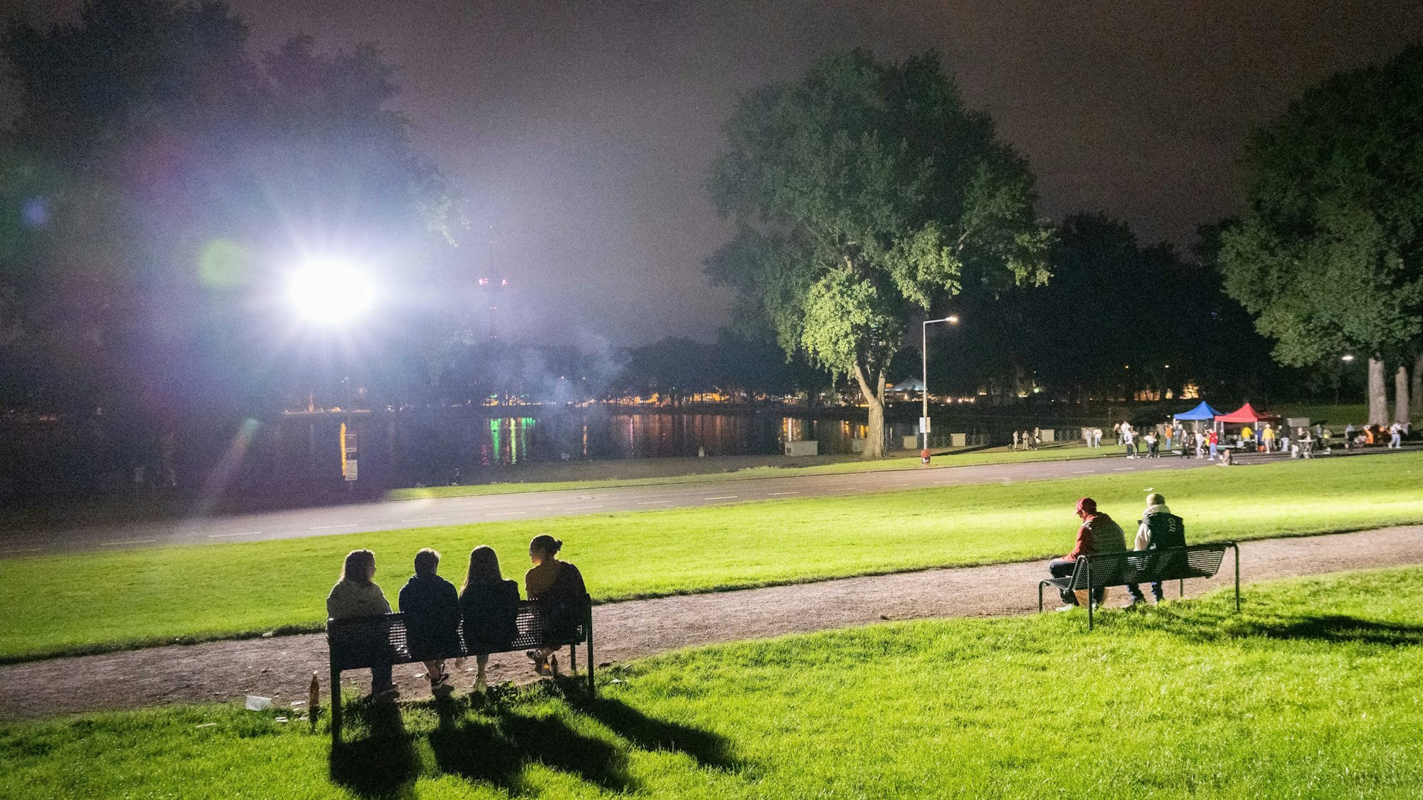 Mehrere Personen sitzen am Aachener Weiher.