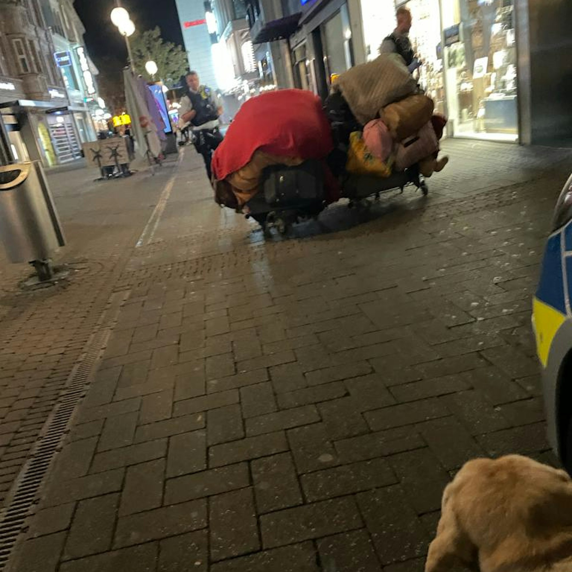 Zwei Polizisten stehen auf der Schildergasse um den Einkaufswagen der Obdachlosen.