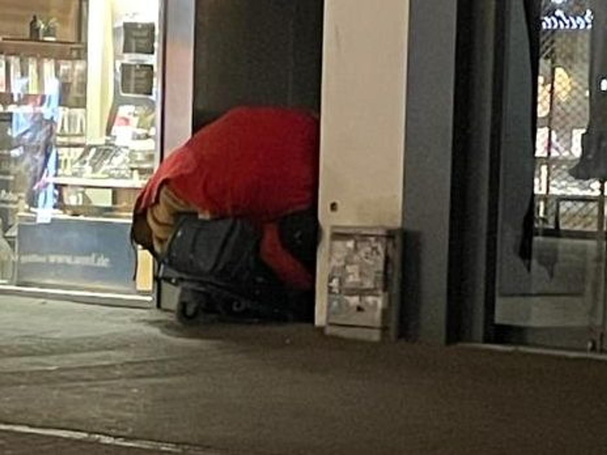 Ein Einkaufswagen einer Obdachlosen mit ihrem Hab und Gut versperrt einen Hauseingang.