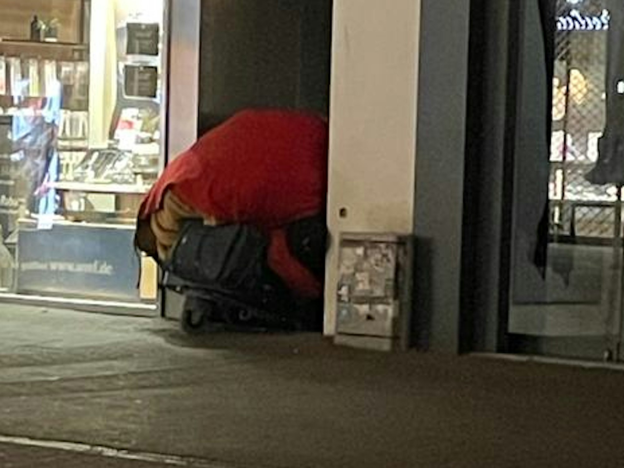 Ein Einkaufswagen einer Obdachlosen mit ihrem Hab und Gut versperrt einen Hauseingang.