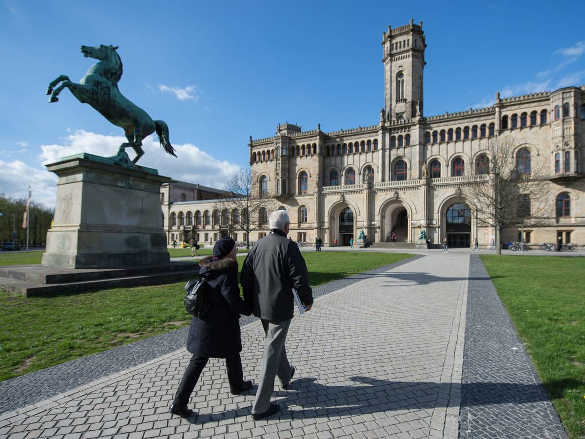 Zwei Passanten gehen auf einem Fußweg zur Leibniz Universität.