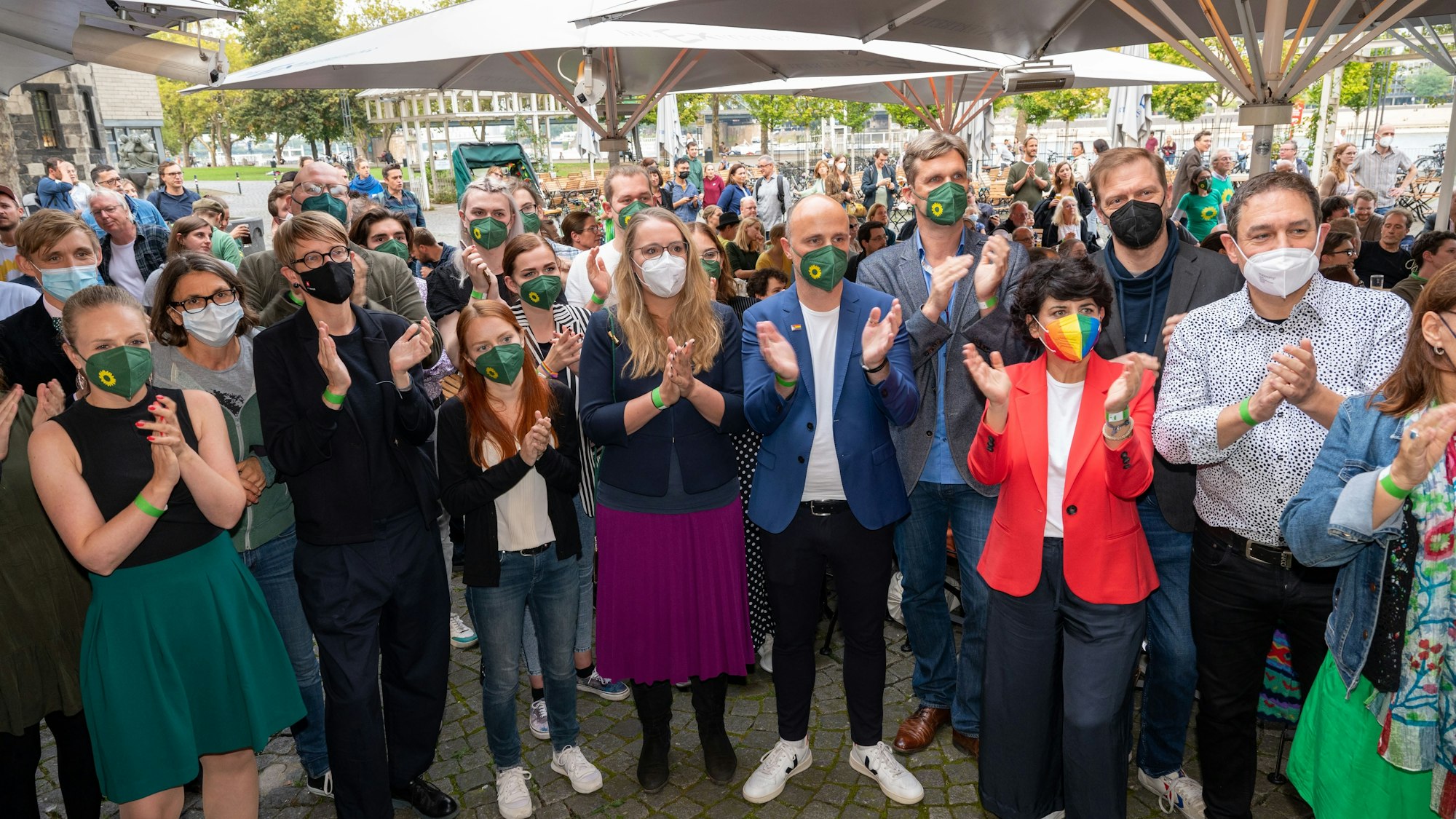 Die Direktkandidaten der Grünen Katharina Dröge und
Sven Lehmann stehen im Kreise mit anderen Parteimitgliedern und applaudieren.