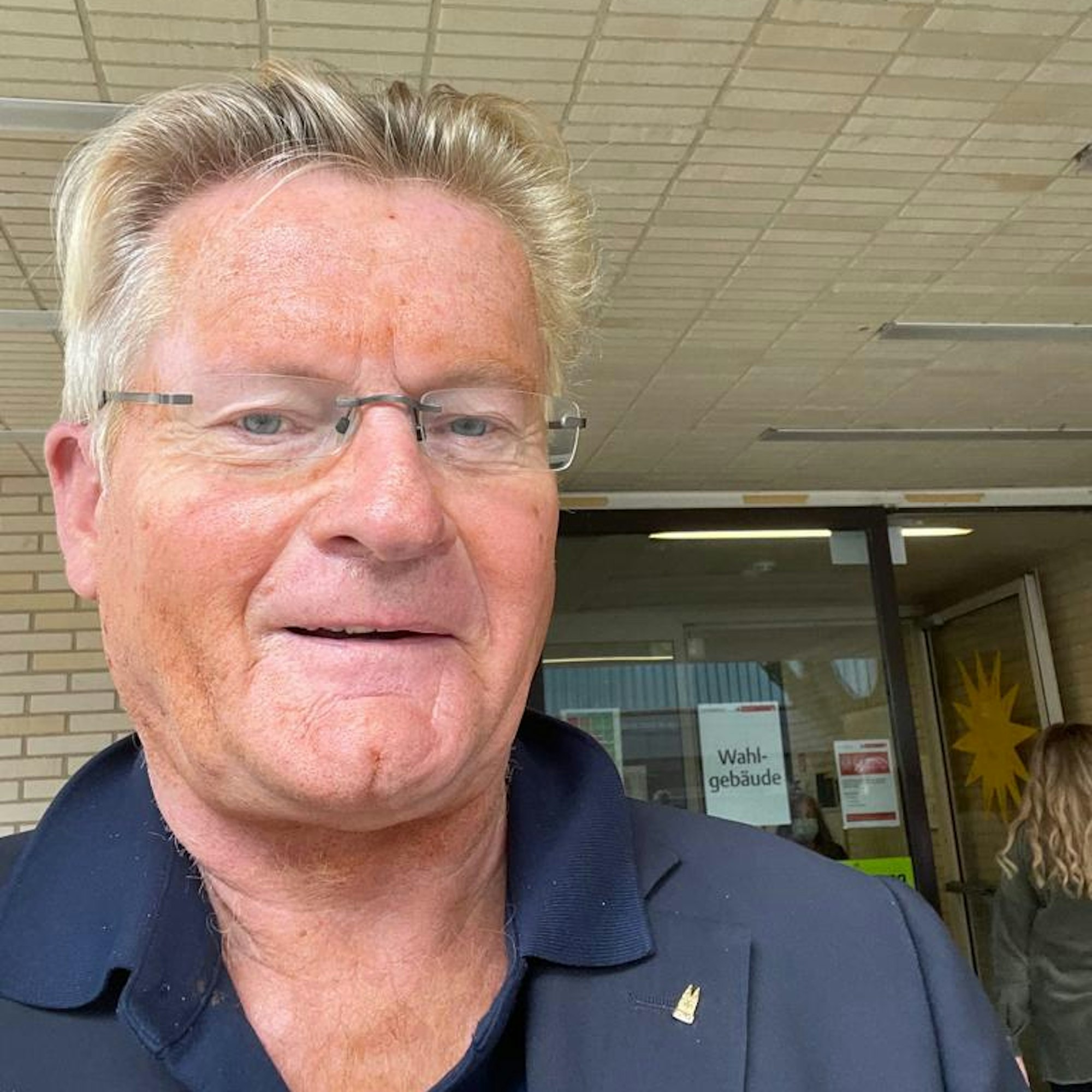 MIchael Trippel macht ein Selfie vor einem Schulgebäude.