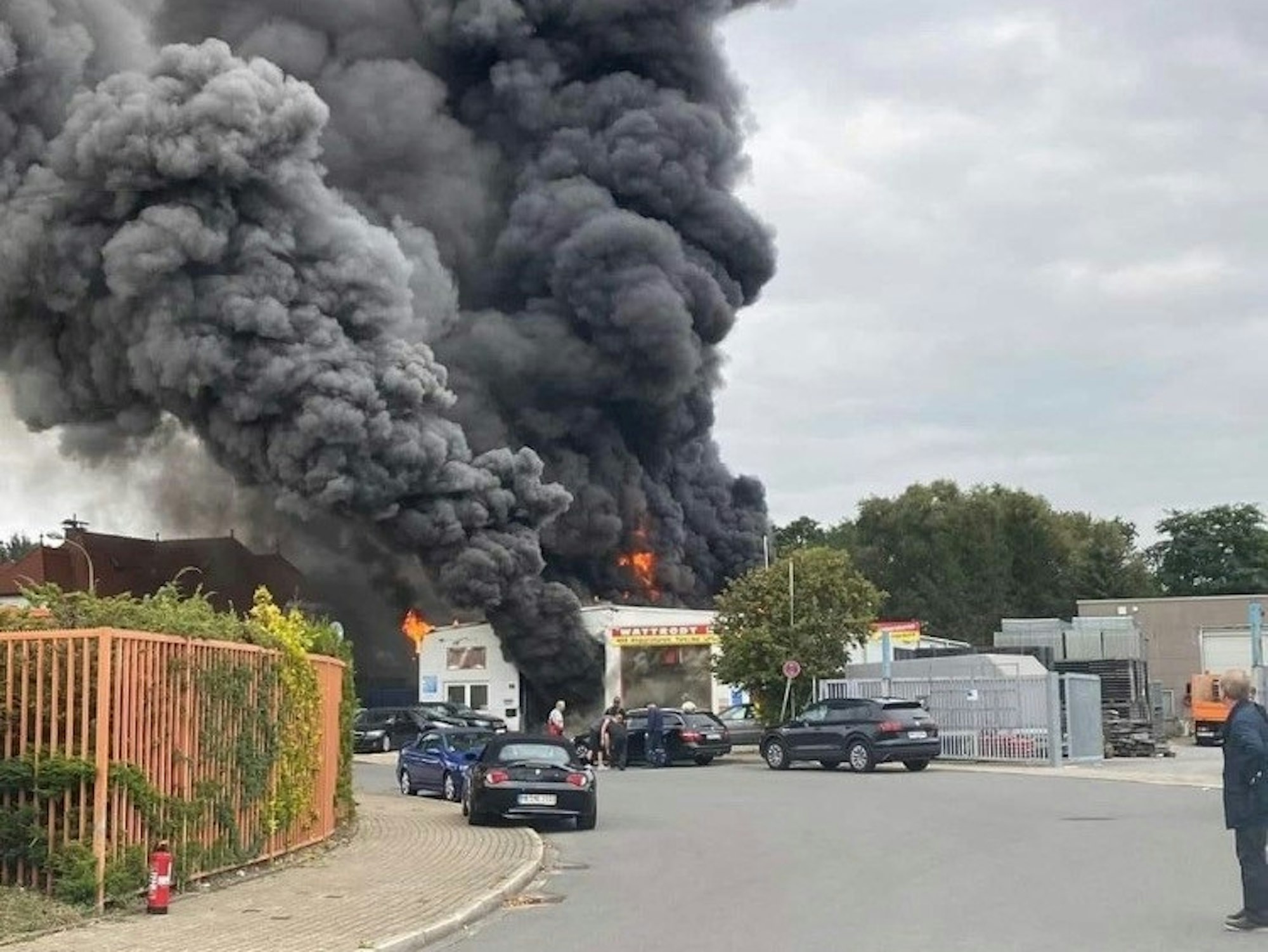 Aus der Halle einer Autowerkstatt schlagen Flammen. Schwarzer Rauch steigt in den Himmel.