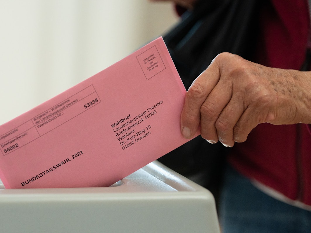 Eine Frau wirft in einem Briefwahlbüro ihren Wahlschein in einer Wahlurne.