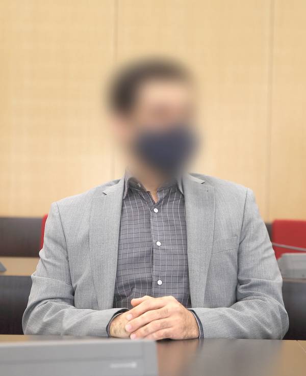 Der angeklagte Arzt sitzt mit Maske im Saal des Landgerichts