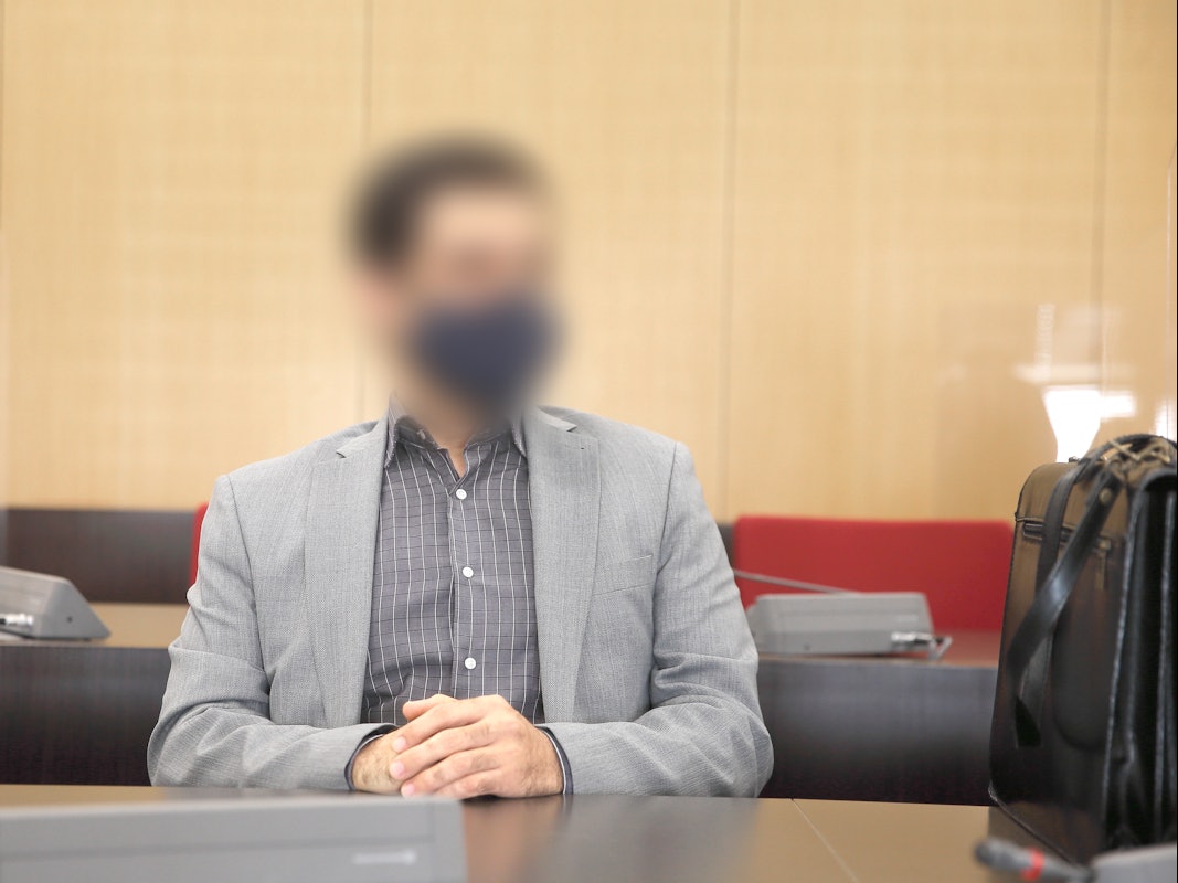 Der angeklagte Arzt sitzt mit Maske im Saal des Landgerichts.