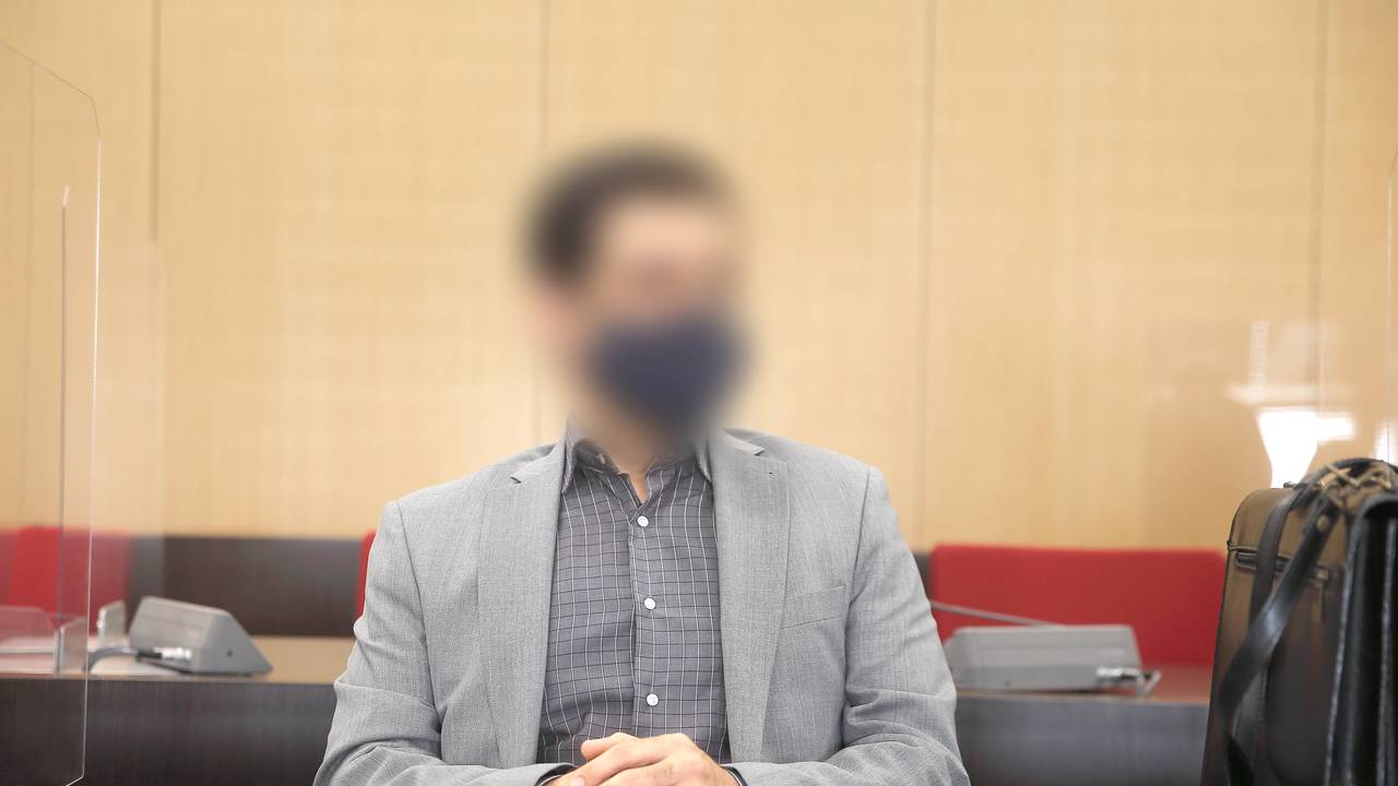 Der angeklagte Arzt sitzt mit Maske im Saal des Landgerichts