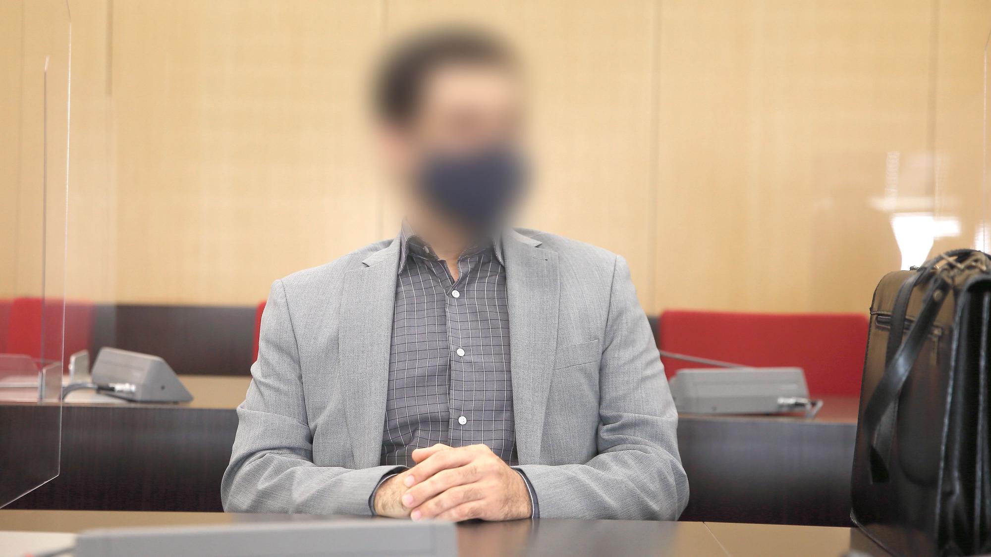 Der angeklagte Arzt sitzt mit Maske im Saal des Landgerichts.