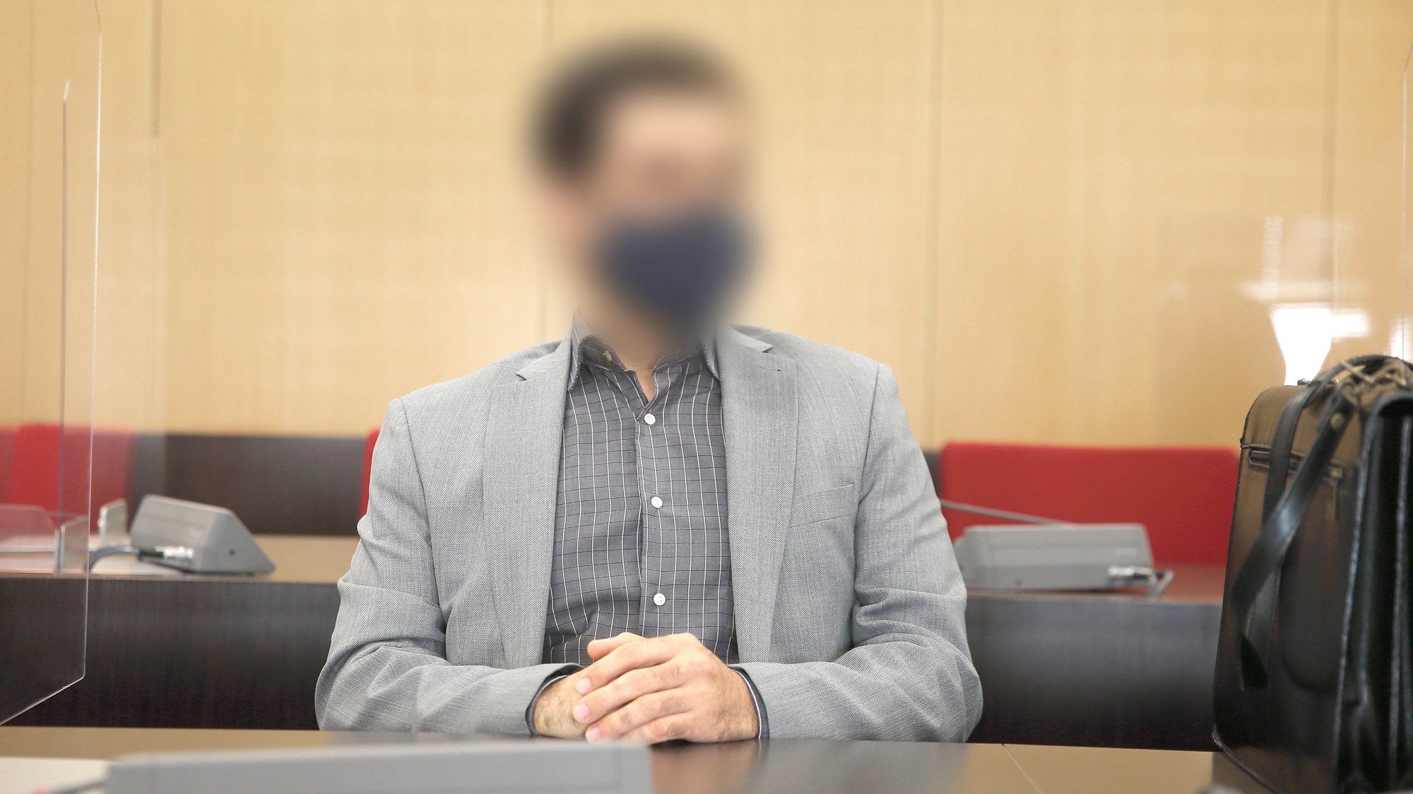 Der angeklagte Arzt sitzt mit Maske im Saal des Landgerichts.