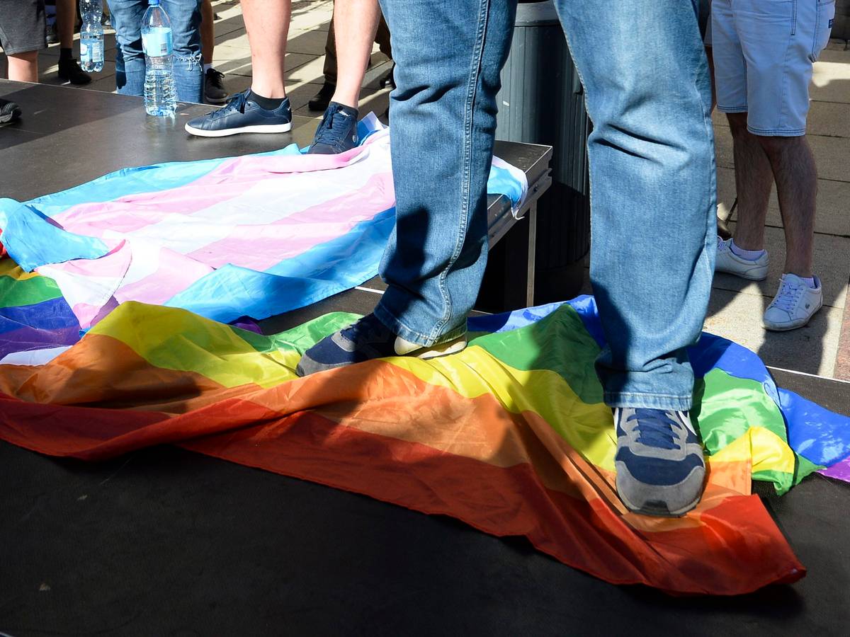 Ein Mann steht in Warschau, Polen, auf einer Regenbogenflagge.