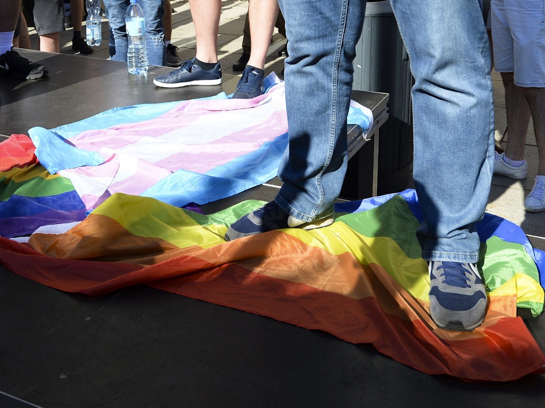 Ein Mann steht in Warschau, Polen, auf einer Regenbogenflagge.