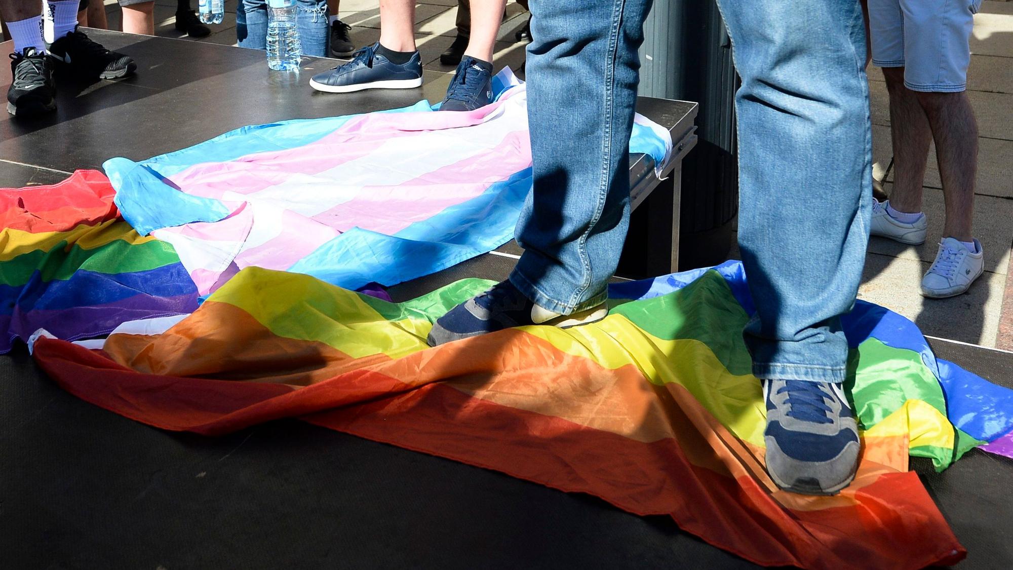 Ein Mann steht in Warschau, Polen, auf einer Regenbogenflagge.