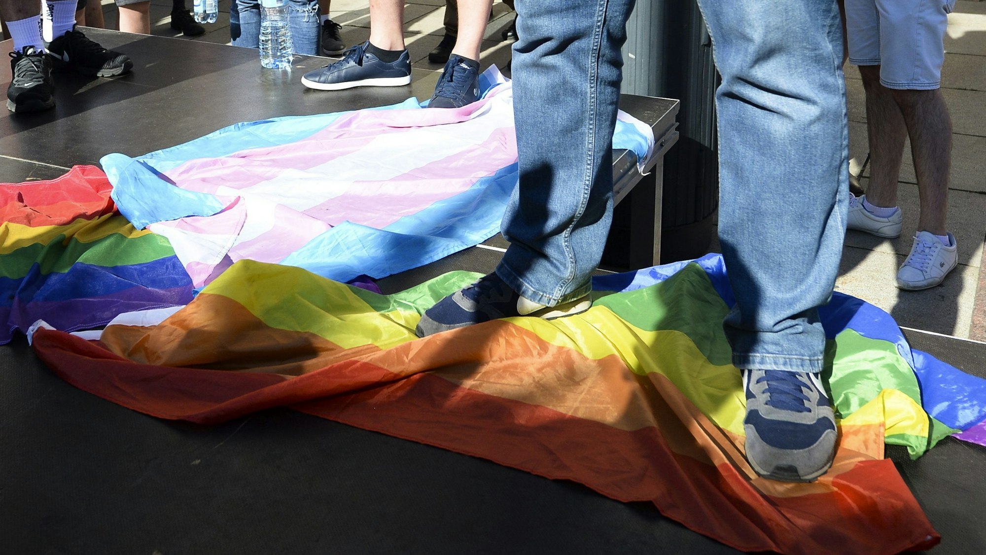 Ein Mann steht in Warschau, Polen, auf einer Regenbogenflagge.