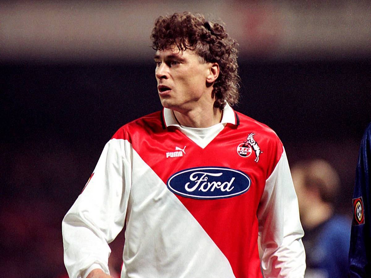 Toni Polster ist fokussiert. Er trägt ein rot-weißes Köln-Trikot von Puma mit dem Ford-Logo auf der Brust.