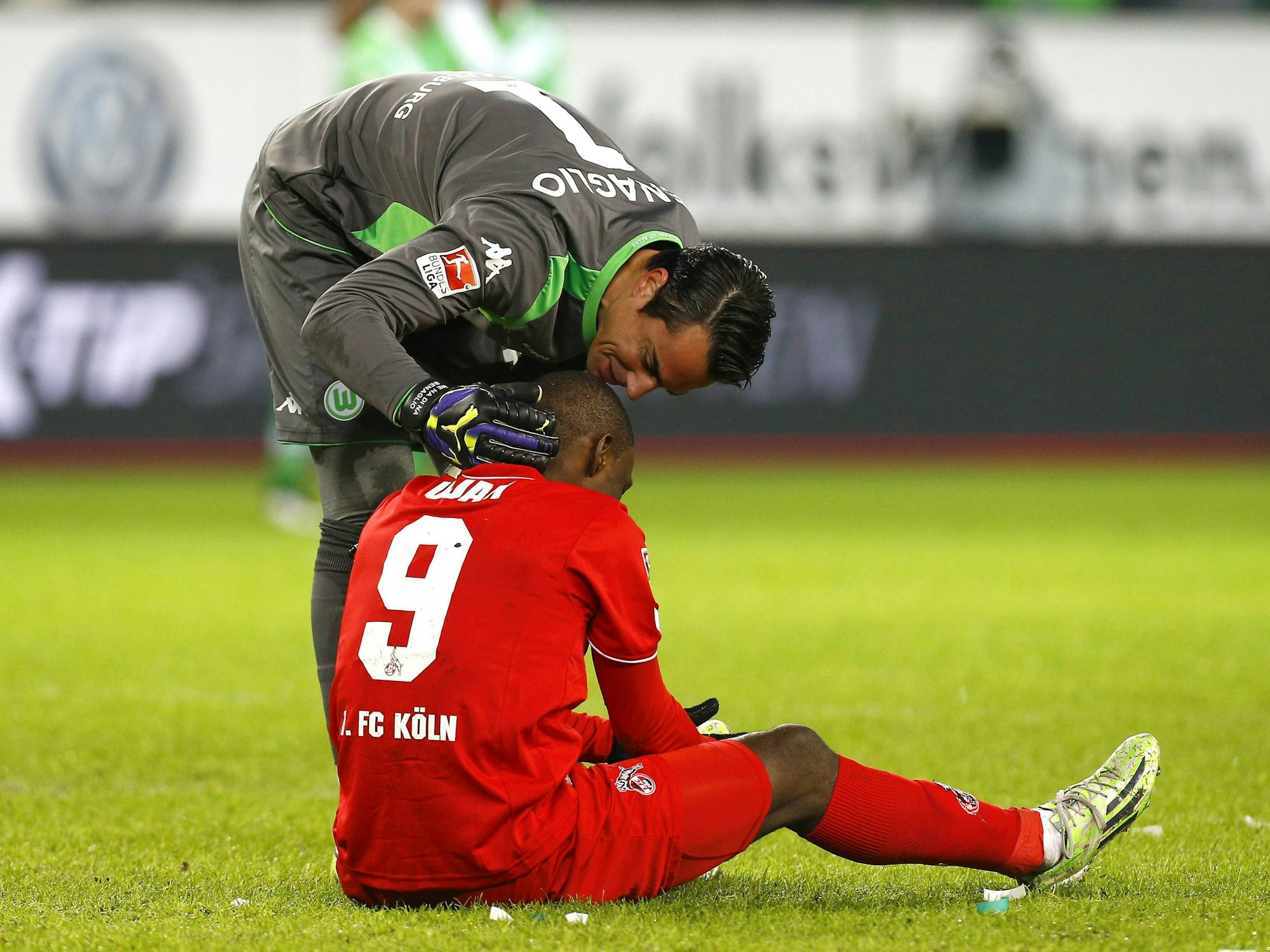 Anthony Ujah sitzt auf dem Boden, Diego Benaglio beugt sich über hin und redet ihm gut zu.