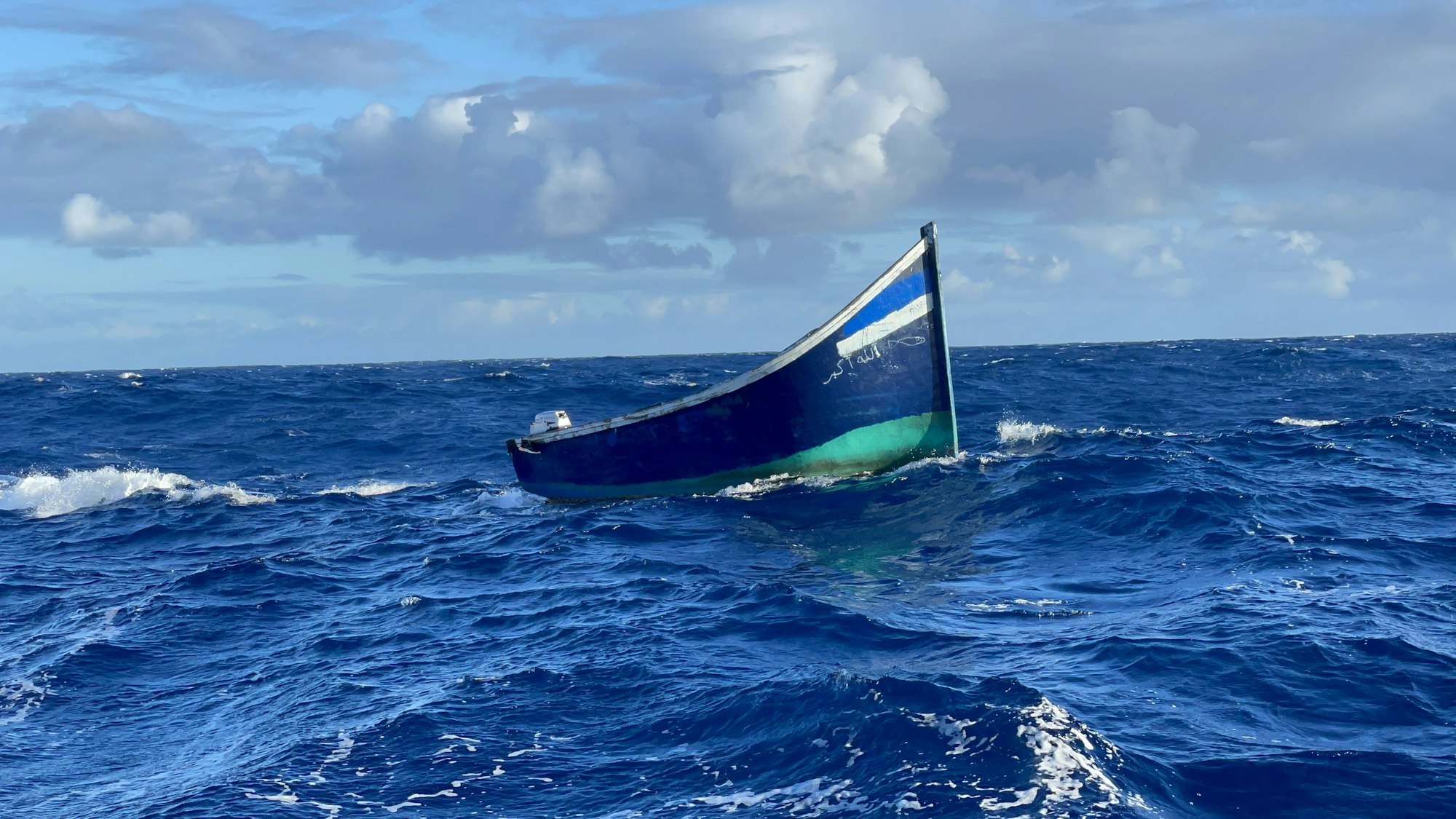 Ein Holzboot treibt auf dem Meer.