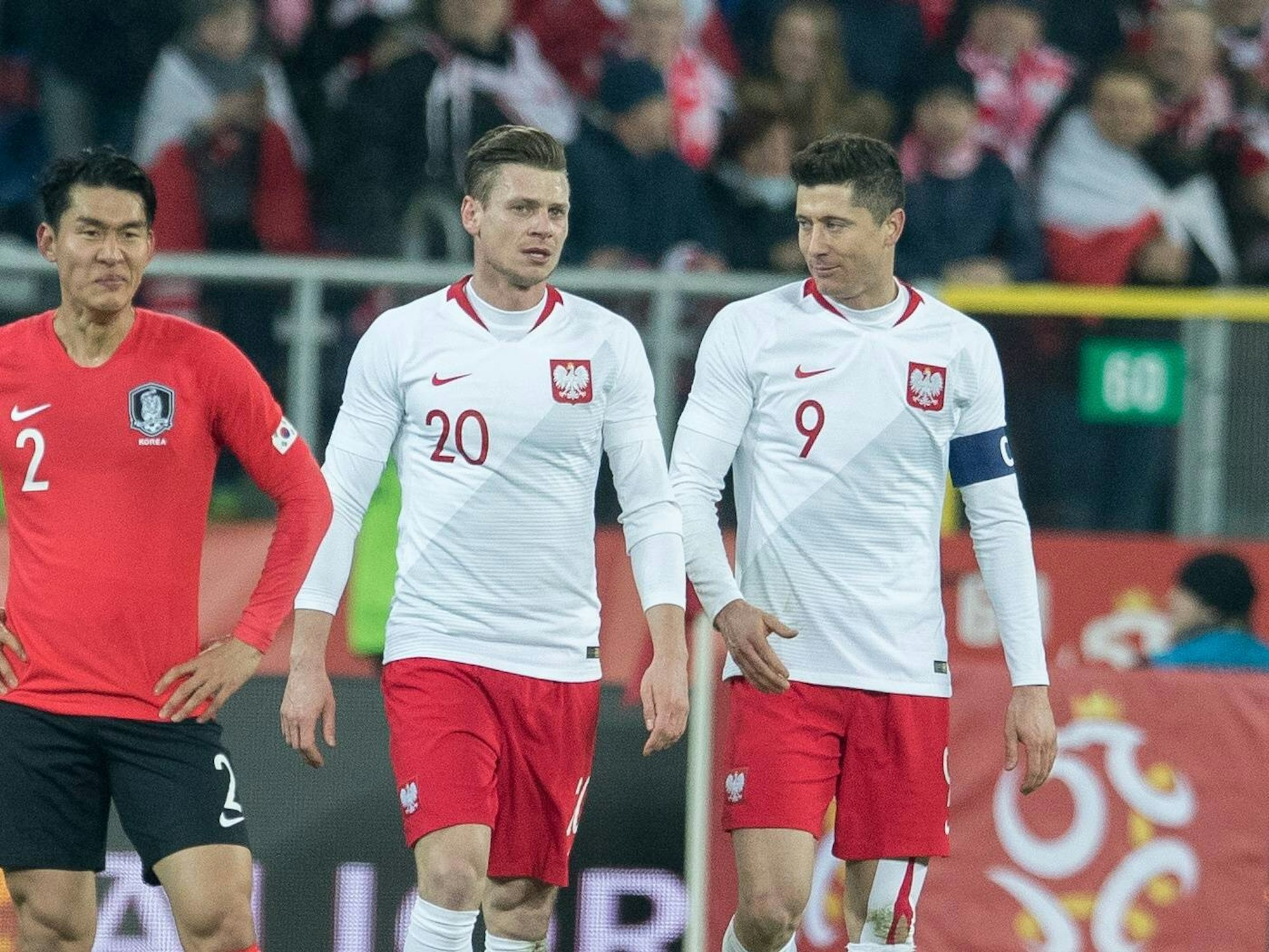 Lukasz Piszczek und sein Kollege Robert Lewandowski gehen gemeinsam über das Feld, links von ihnen steht ein südkoreanischer Spieler.