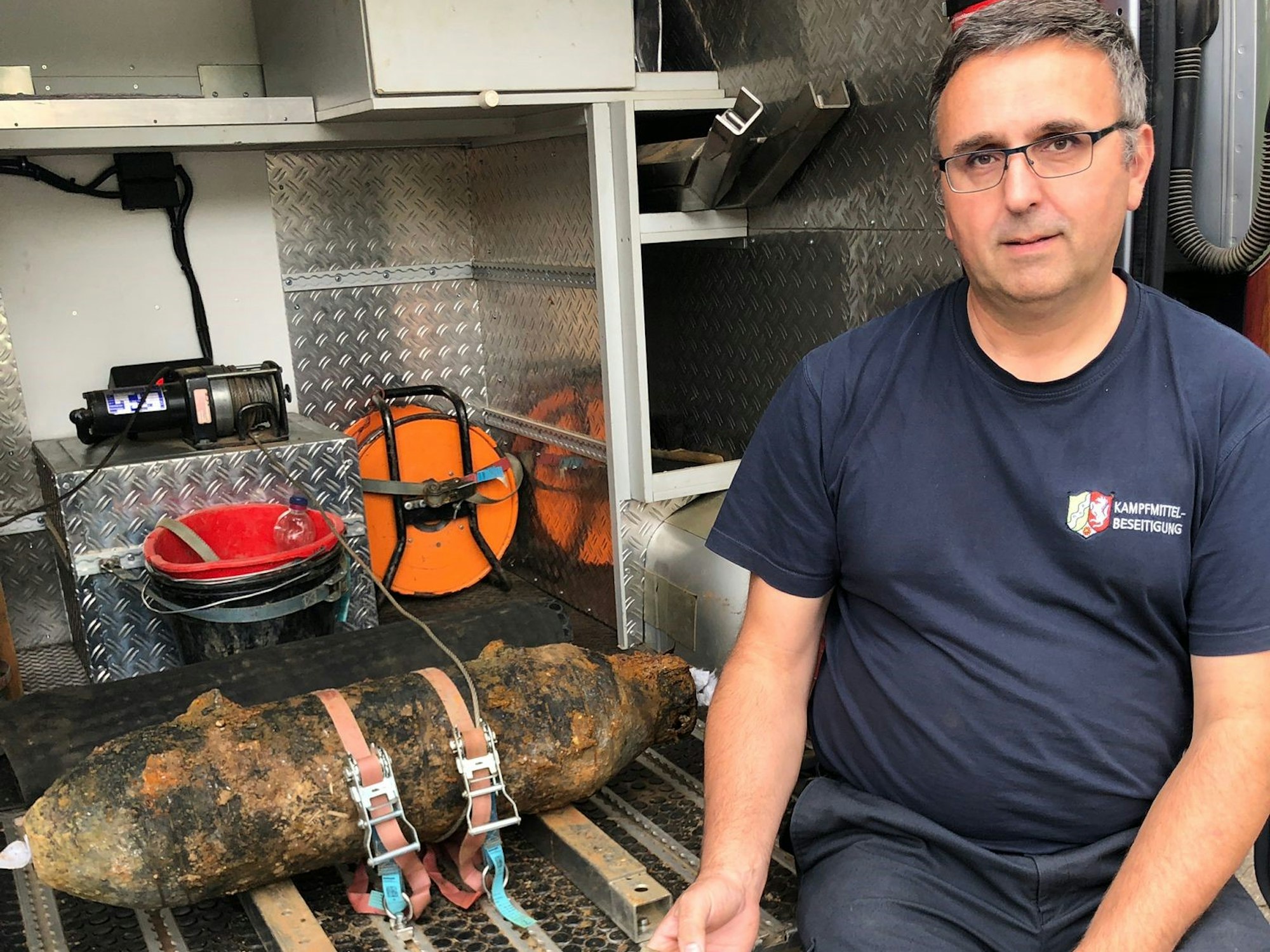 Mitarbeiter Michael Daenecke vom Kampfmittelbeseitigungsdienst sitzt neben einer entschärften Bombe.