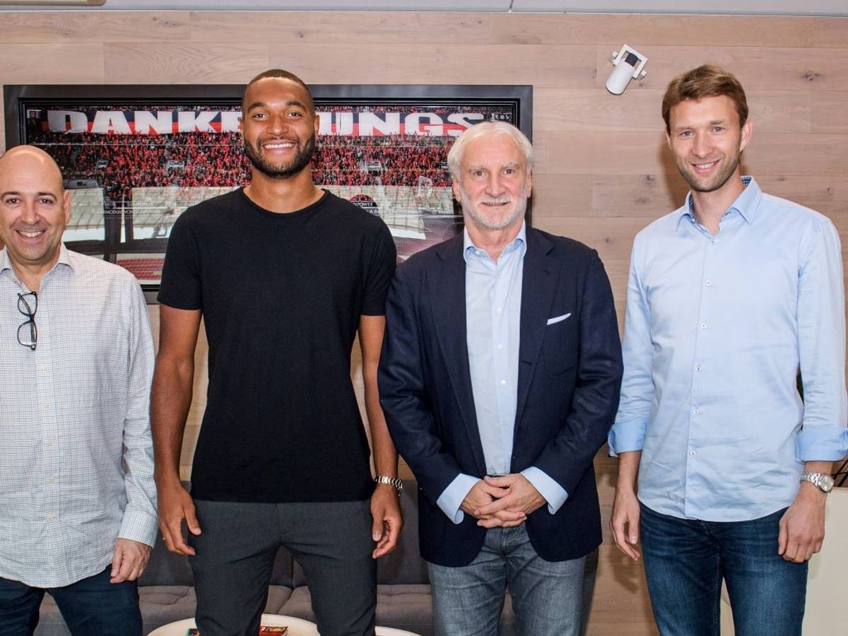 Jonathan Tah posiert zusammen mit Geschäftsführer Fernando Carro, Rudi Völler und Simon Rolfes vor einem Bild, das im Stadion aufgenommen worden ist.