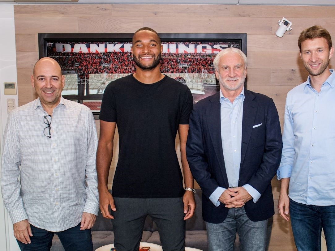 Jonathan Tah posiert zusammen mit Geschäftsführer Fernando Carro, Rudi Völler und Simon Rolfes vor einem Bild, das im Stadion aufgenommen worden ist.