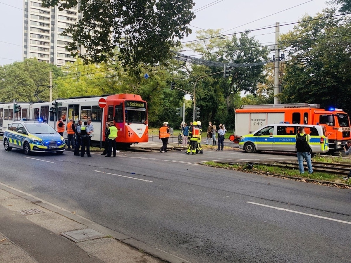 Polizisten, Feuerwehrmänner und Rettungskräfte stehen um eine Straßenbahn.