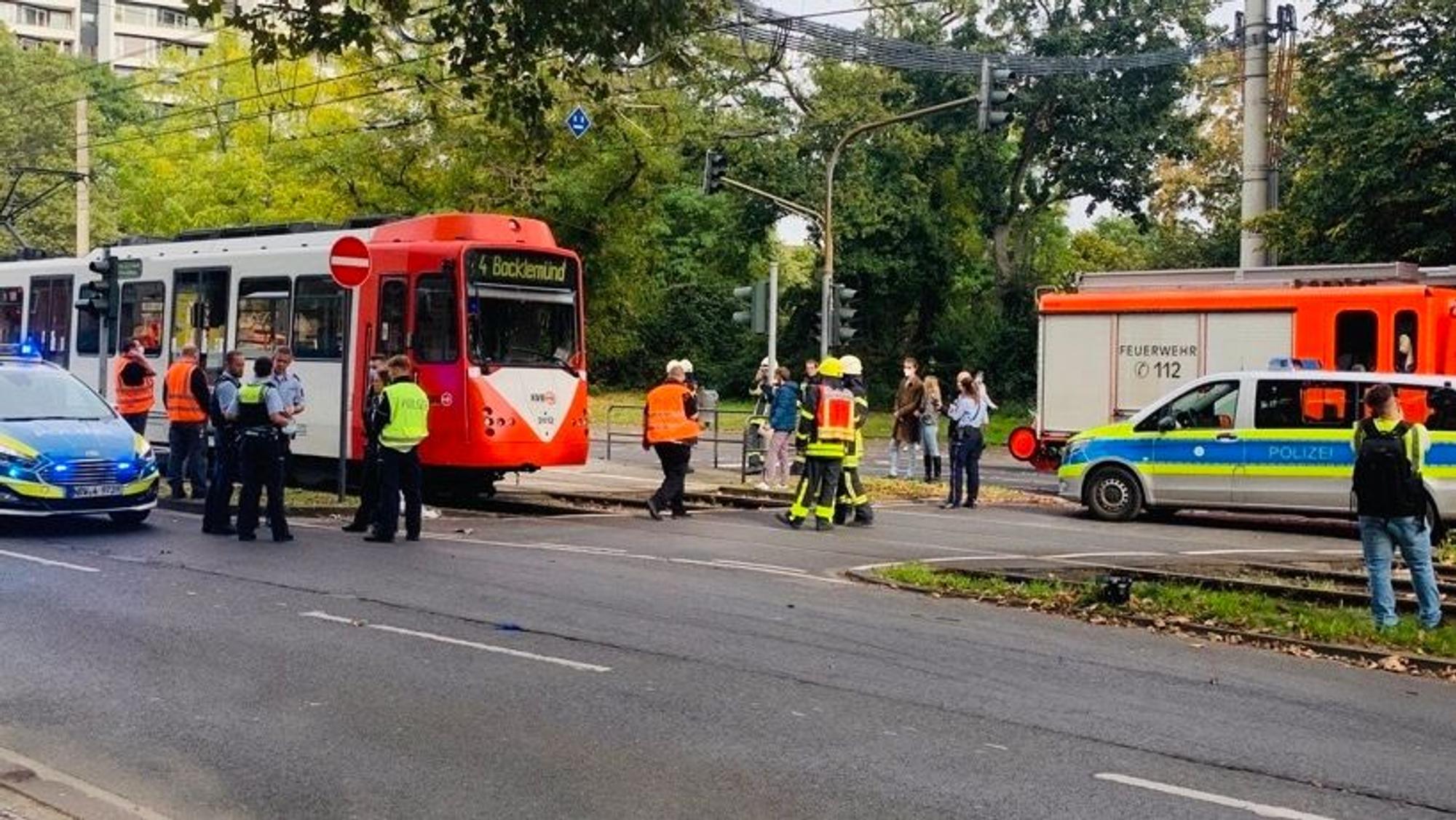 Polizisten, Feuerwehrmänner und Rettungskräfte stehen um eine Straßenbahn.
