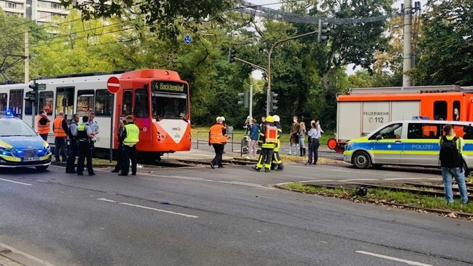 Polizisten, Feuerwehrmänner und Rettungskräfte stehen um eine Straßenbahn.