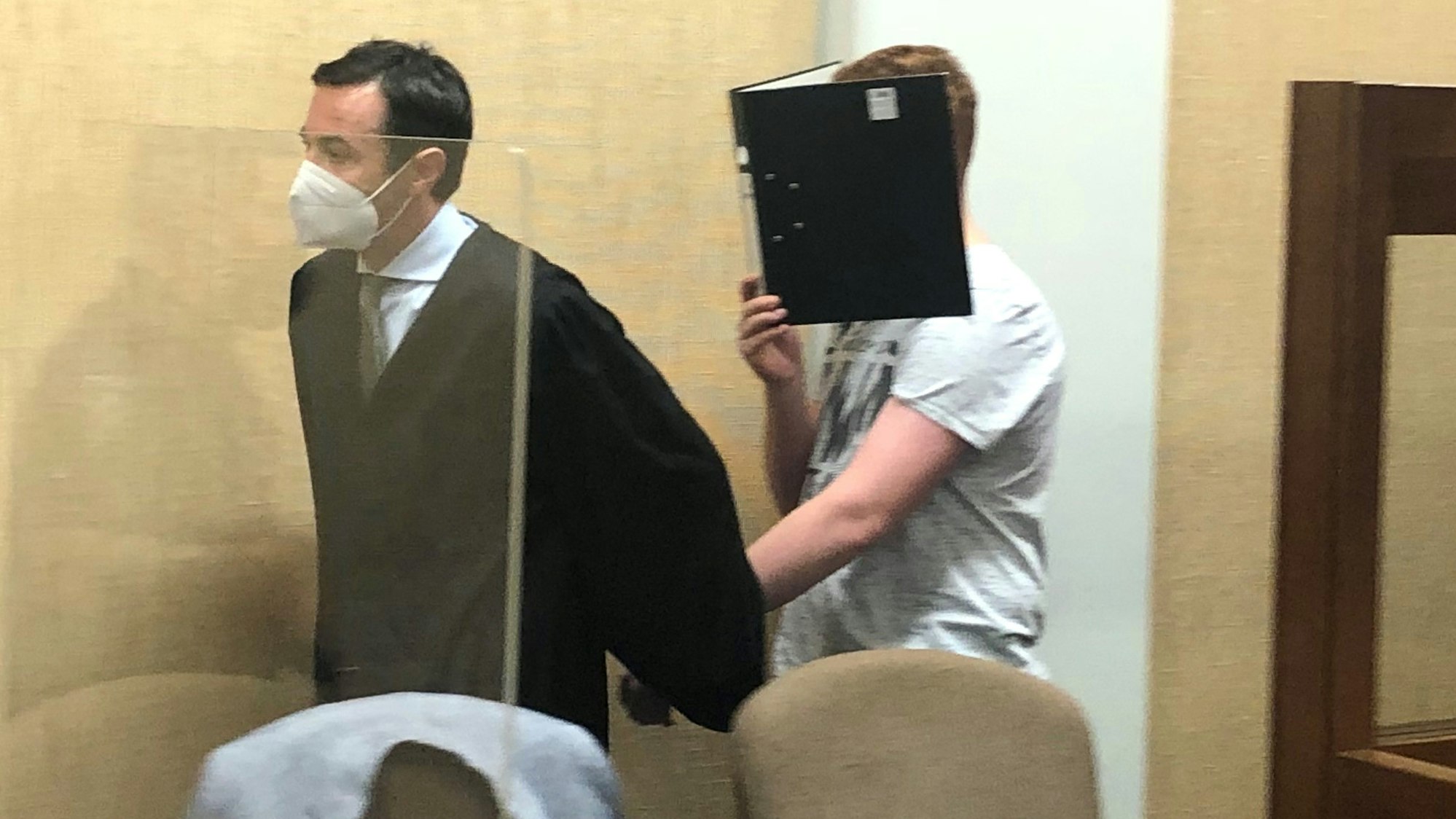 Der Anwalt hält seinen Mandanten an der Hand und lotst ihn in den Gerichtssaal.