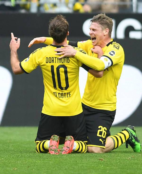Mario Götze und Lukasz Piszczek knien auf dem Rasen, Piszczek will Götze umarmen.